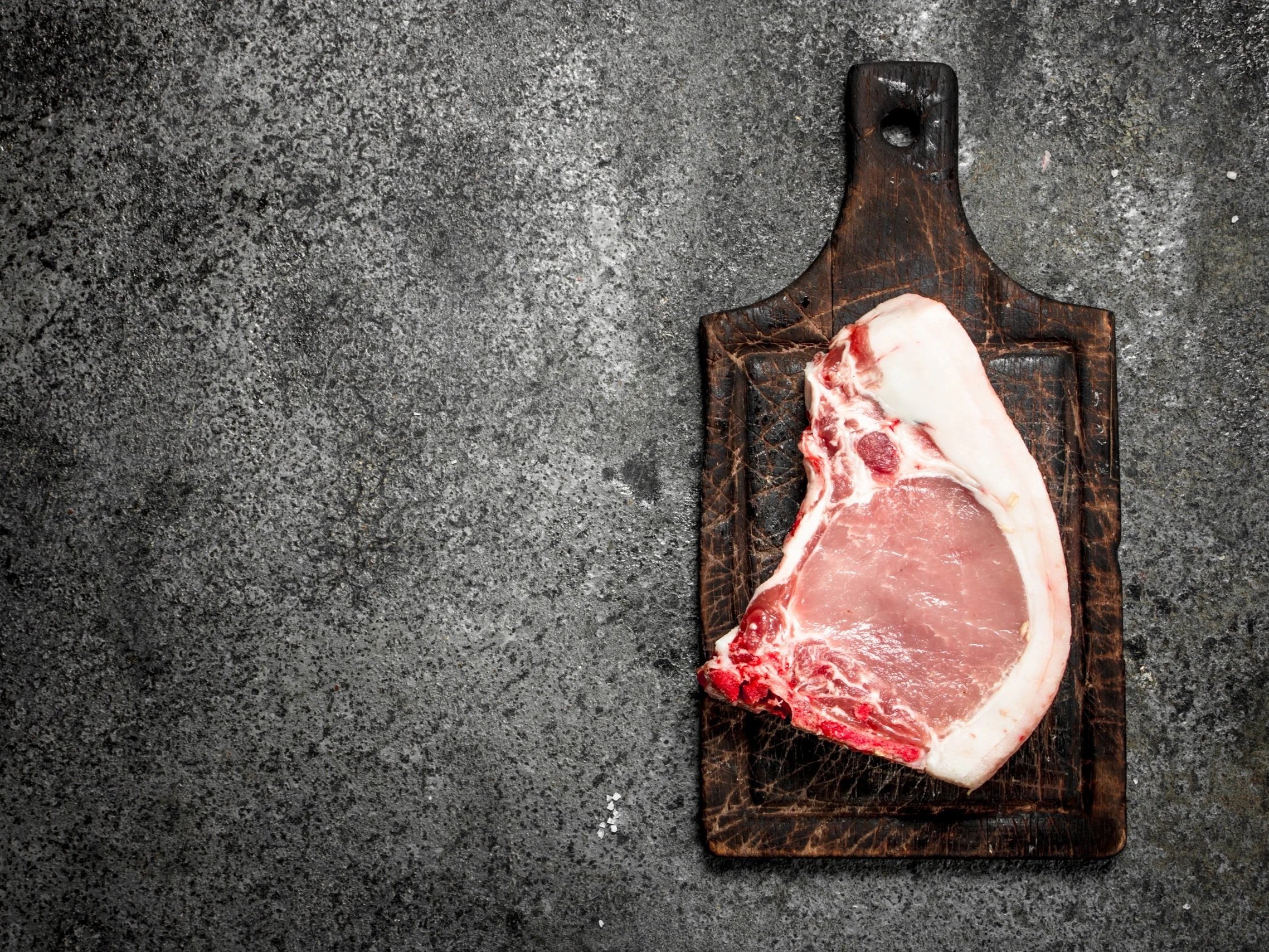 Juicy, medium-rare steak being sliced on a wooden cutting board, showcasing its tender pink interior and seared crust, with a carving knife and fork positioned for serving.